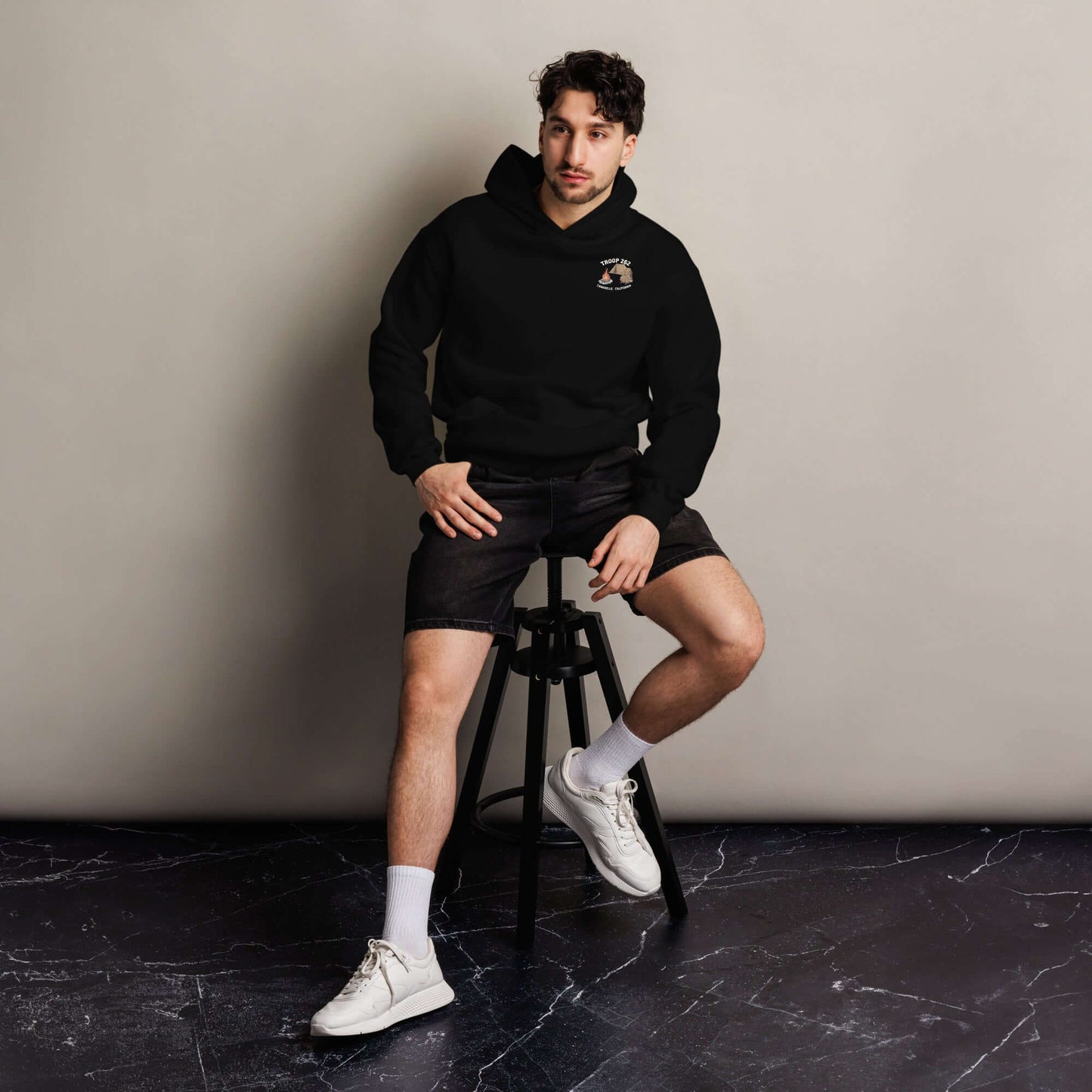 Man wearing Adult Unisex Oversized Hoodie in black, sitting on a stool in casual style.